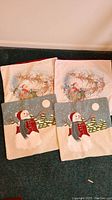 Four Christmas pillow shams laid out on carpet. Two with Santa Claus and reindeer, two with snowman designs, measuring approximately 18 x 18 inches each.