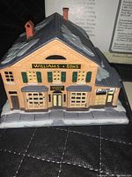 Front view of ceramic country store model with store signage and snow-covered roof.
