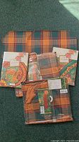 Lot of assorted fall color table linens including packaged placemats, napkins, and table runner with autumn patterns and a turkey motif.
