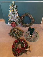 All five Christmas decorations arranged on floor in overall view showing tree, wreaths, and swags