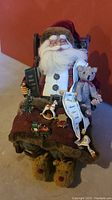 Front view of the detailed sleeping Santa figure seated with accessories including teddy bear, book, and Christmas decorations.