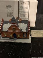 Front view of ceramic town offices building with snow on roof and ground, showing arched blue door and windows, with Certificate of Authenticity in background.