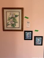 Three framed art pieces displayed on a wall: one large floral botanical print and two smaller matching blue-toned window scene prints with 3D effects.