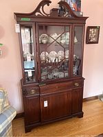 Two-piece wooden china cabinet with glass doors and upper display shelves.