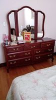Full front view of wood dresser with attached triple mirror and items on top removed in the lot.