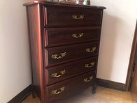 Straight-on front view of the wood dresser showing five drawers with gold handles.