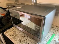 Panasonic microwave oven on kitchen countertop showing full front and side view with stainless steel finish and mirrored door.