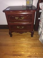 Front view of the side table showing two closed drawers and carved wood details.