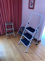 Photo showing all three step stools with varying sizes and steps in a room on wood floor.