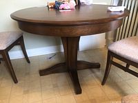 Front view of round wood table with pedestal base and chairs