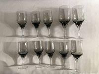 Ten clear crystal wine glasses laid out on a flat surface in two rows, showing all glasses together for quantity and condition.