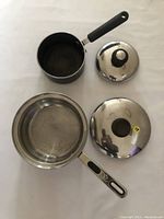 Two cooking pots with lids, small Lagostina non-stick and large Oneida stainless steel, displayed on white background.