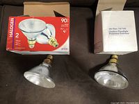Two outdoor floodlight bulbs with their original packaging; one 90W PAR38 halogen bulb and one 150W outdoor floodlight bulb.