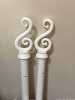 Close-up of the swirl-shaped plastic ends of one towel bar showing cream color with gold embossing.