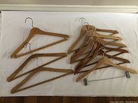 Nine wooden hangers on white background, various wood finishes, three hangers with visible markings indicating origin (Italy, Denmark).
