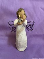 Front view of Willow Tree Angel of Hope figurine with wire wings holding a small lighted candle or flame.
