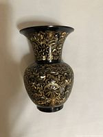 Front view of black and gold etched brass vase with floral patterns