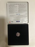 Coin displayed in black velvet insert inside metal case with text about Canada Millennium.