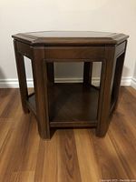 Front view of hexagonal wooden coffee table showing legs and lower shelf, wooden frame in dark brown color.