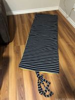 Top view of the foam pad lying flat showing striped black and gray side of the cover, revealing rectangular shape and size.