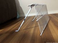 Side view showing white metal wire shelf, slatted design, and adjustable back brackets with peeling white paint.