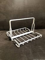 Photo of white metal napkin holder showing wire base and vertical sliding bar with knob.