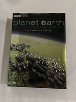 Front cover of the Planet Earth DVD set showing a herd of animals in a green landscape with the title and brand.