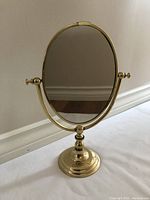 Rotating vanity mirror front and side view showing the intact mirror and gold-tone heavy metal frame and base