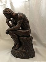 Side angle showing muscular anatomy and contemplative pose of the sculpture