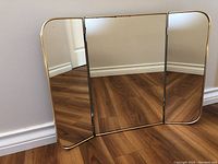 Front view of the tri-fold mirror fully opened on wooden floor