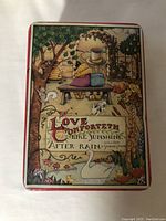 Top view of rectangular tin box showing detailed illustration of children sitting on bench, animals, flowers and Shakespeare quote on lid