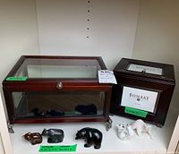 Various animal figurines in front of the Bombay Company box and glass display display box on a shelf
