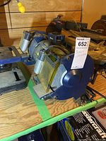 Side view of Mastercraft bench grinder showing dual grinding wheels, power cord, and spark guards.