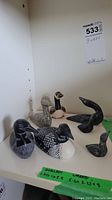 Six carved bird figures displayed on shelf, varying in sizes and styles.