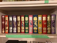 Thirteen slipcased volumes displayed side by side on shelf showing full set and color order.