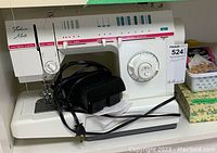 Front angled view of Singer Fashion Mate FM-22C sewing machine showing sewing machine, foot pedal, power cord, and part of the sewing notions box on shelf.