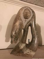 Front-left view of abstract curved stone sculpture with white incised detailing