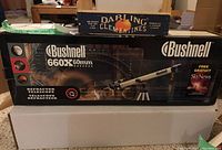 Boxed Bushnell 660X 60mm refractor telescope. Box shows brand name, model, and image of telescope with tripod.
