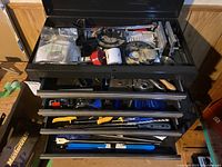 Top view of open tool chest drawers showing hand tools and drill bits scattered inside.