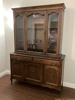 Full view of the wooden china cabinet showing the glass door top section and the wooden bottom section with drawers and cabinet doors.