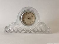 Crystal mantle clock with clear glass and diamond-cut pattern showing clock with Roman numerals.