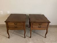 Pair of matching solid wood end tables with scalloped edges and double drawers, front view