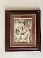 Framed landscape art piece in wood and gold frame with matte border on wall.