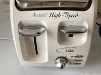 Close-up photo of Avante High-Speed Deluxe toaster front panel with chrome levers and control knob.