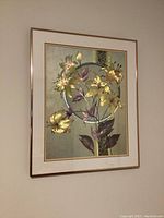 Full view of framed metallic lily artwork mounted on wall.