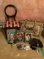Full lot view showing three acrylic boxed Asian dolls, wooden doll chair, woven purse with seashells, and various small decorative items.