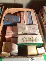 Box containing approximately 15 assorted boxed Avon perfume and toiletry items with vintage-style packaging.