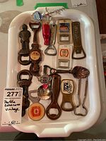 Tray with 14 bottle openers and corkscrew, showing size and overall condition