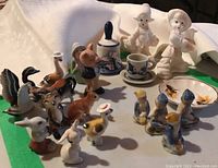 Ceramic miniature animal and child figurines arranged on a table.