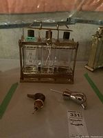 Full view of three labeled glass decanters in brass stand with two bottle stoppers in front and a tag.